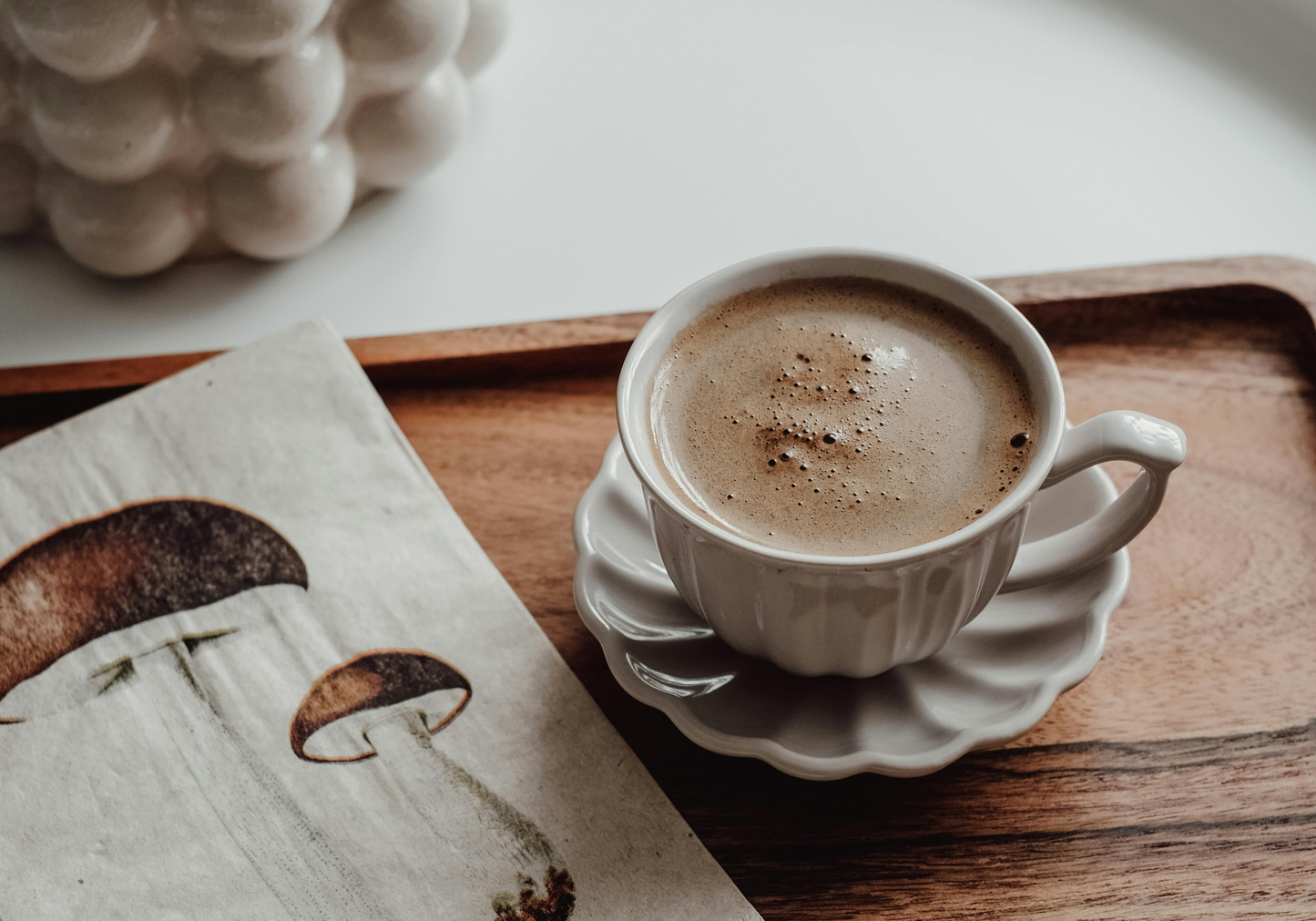 Cup of mushroom coffee on a wooden tray beside a mushroom illustration, representing Strovori functional mushroom coffee in Canada.